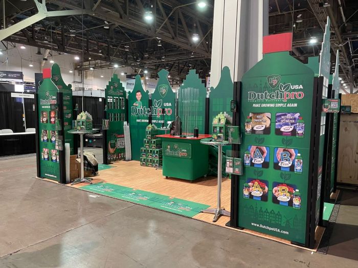 Grüner Inhaker® Messestand von Signalshop.de, individuell gestaltbar mit Logo, ideal für Werbeartikel.