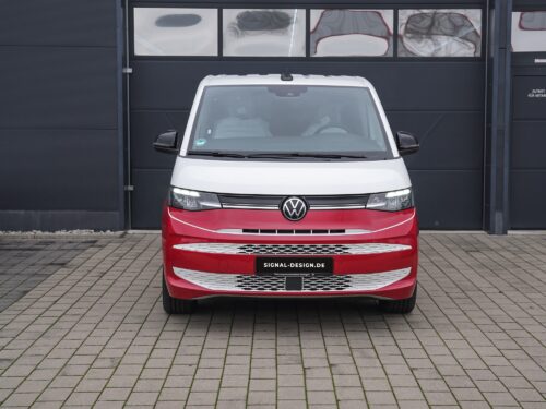 Frontansicht eines VW-Busses mit der atemberaubenden rot-weißen Bicolor-Folierung mit Montage, der auf einer gepflasterten Auffahrt geparkt ist.