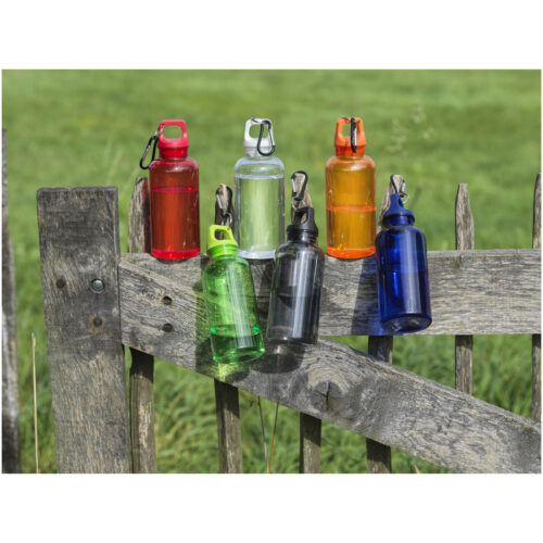 Sechs bunte Wasserflaschen mit Karabinern auf einem Holzzaun vor einem grasbewachsenen Hintergrund.