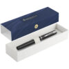 Ein schwarzer Waterman-Stift in einer offenen weißen Geschenkbox mit blauem Deckel, auf dem ein goldenes Emblem und Text angebracht sind.