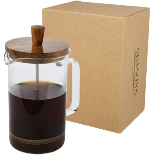 Gläserne French Press mit Kaffee, Holzdeckel, neben einem braunen Karton.