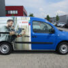 Blauer Bosch-Transporter mit Gestaltungskonzept Premium 699 €, vor den Fabriken geparkt.