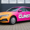 Pink-orangefarbenes Auto mit „Gestaltungskonzept Premium 699€“ auf befestigtem Untergrund.