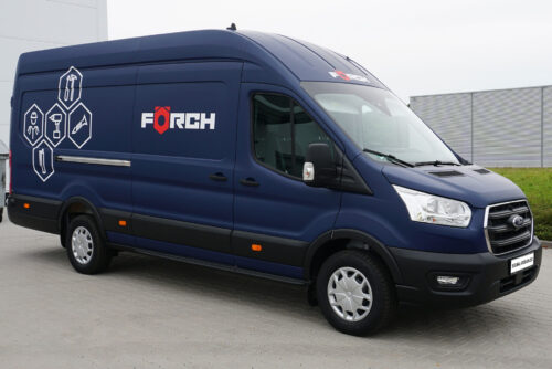 Blauer Förch Lieferwagen mit Gestaltungskonzept Premium 699€ neben einem Zaun.