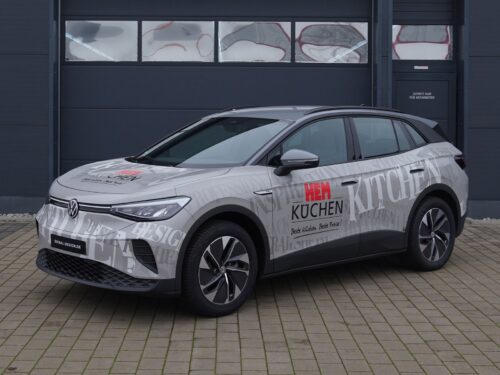 Silberner Volkswagen SUV mit Gestaltungskonzept Premium 699 €, geparkt neben einer dunklen Garage.
