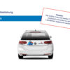 Rückansicht eines weißen Volkswagen mit einem blau-weißen Aufkleber auf dem Kofferraum.